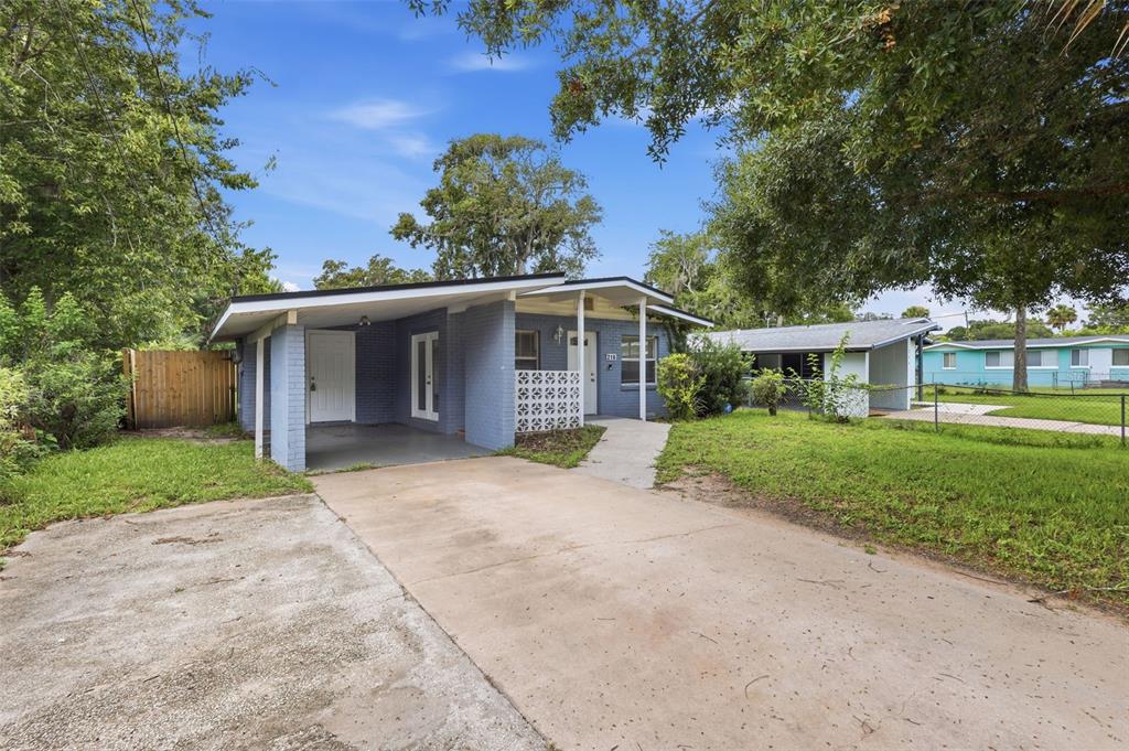 A blue brick house with a carport and a concrete driveway under a clear sky — 216 GRAHAM STREET, DAYTONA BEACH, FL