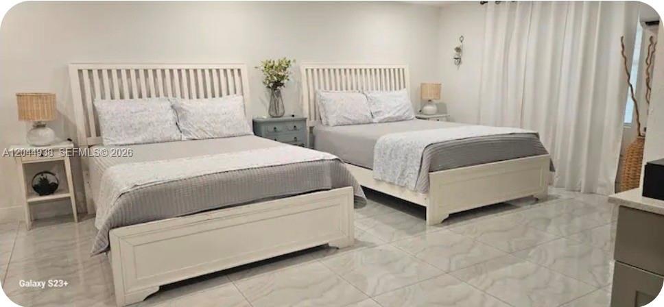 A bedroom features two white wooden beds with grey bedding and tile flooring — 144 NW 7th Ave # 2, Dania Beach FL 33004, DANIA BEACH, FL