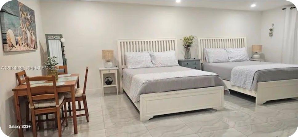 A bedroom features two white wooden beds, a small dining table, and light-colored tile flooring — 144 NW 7th Ave # 2, Dania Beach FL 33004, DANIA BEACH, FL