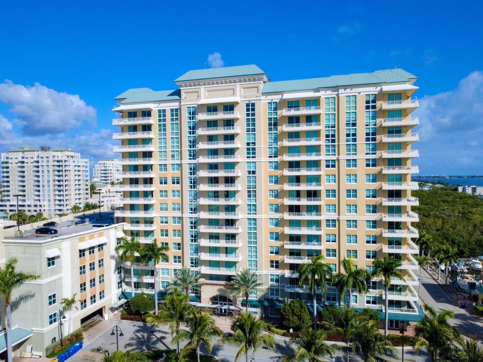 An aerial view of a multi-story tan residential building with balconies and palm trees — 625 Casa Loma Boulevard # 1206, Boynton Beach FL 33435, BOYNTON BEACH, FL