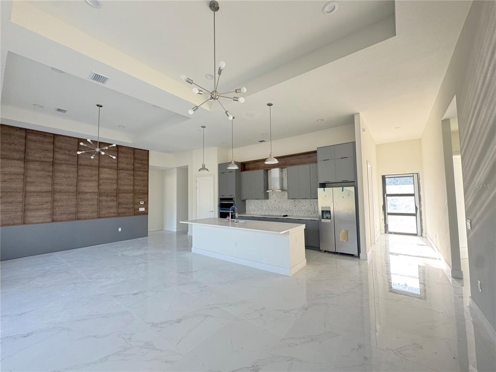 A modern open-concept kitchen and living area features marble floors, gray cabinetry, and wood paneling — 23356 ROSEWOOD AVENUE, PUNTA GORDA, FL