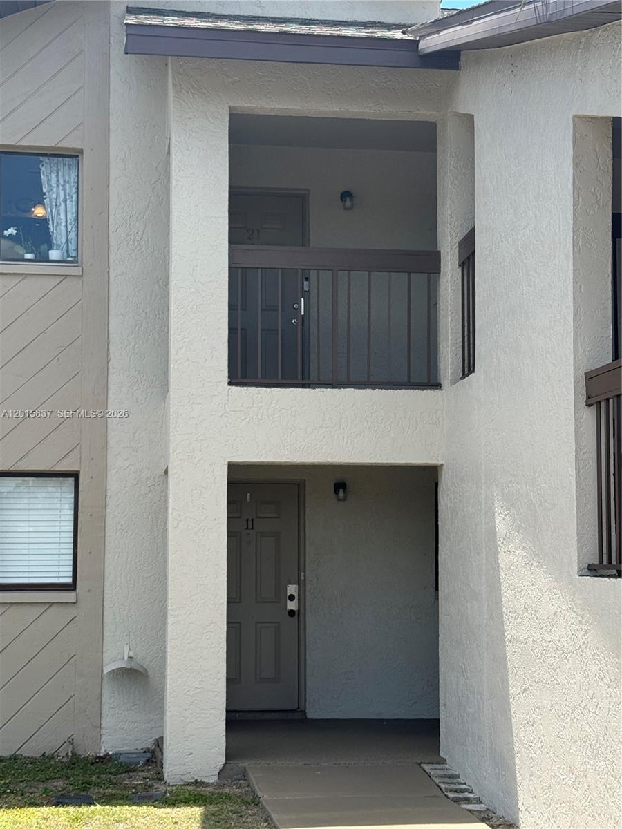 The exterior view shows two stacked apartment unit entrances with brown doors and railings — 2221 E 5th street # 21, Lehigh Acres FL 33936, LEHIGH ACRES, FL