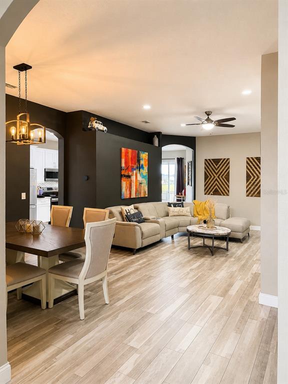 An open-concept living and dining area features wood-look tile flooring and a dark accent wall — 9880 TIVOLI CHASE DRIVE, ORLANDO, FL