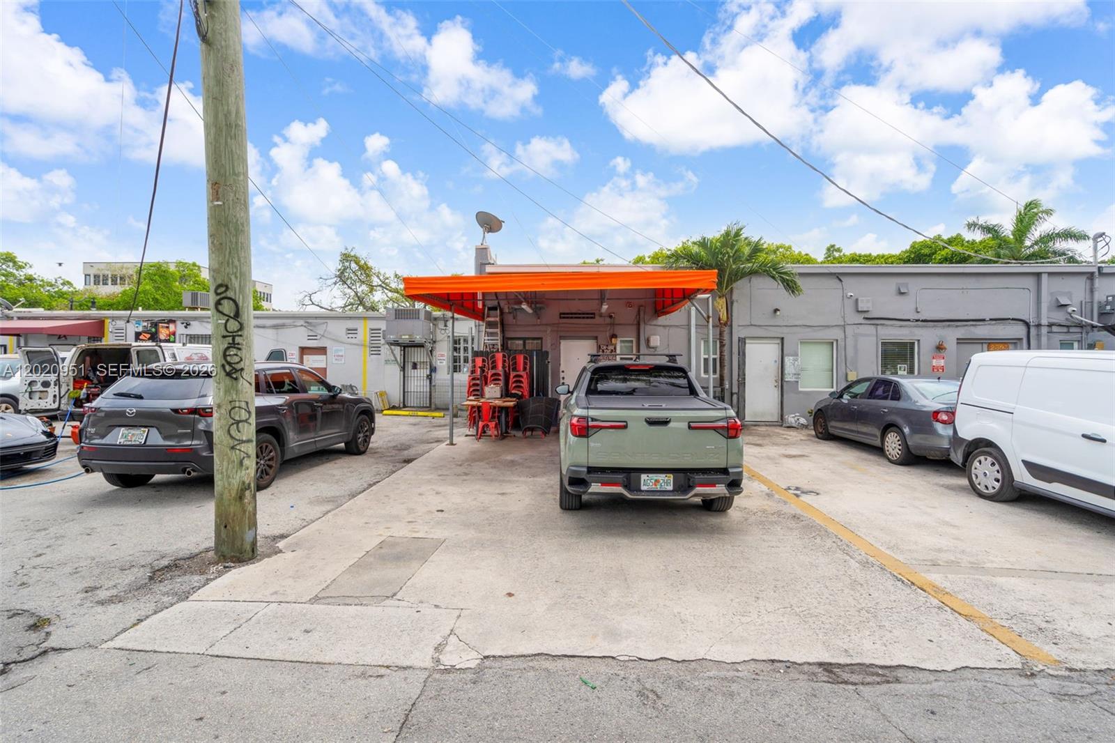 A paved parking area sits in front of a commercial building with an orange awning — 2389 SW 22nd St, Miami FL 33145, MIAMI, FL