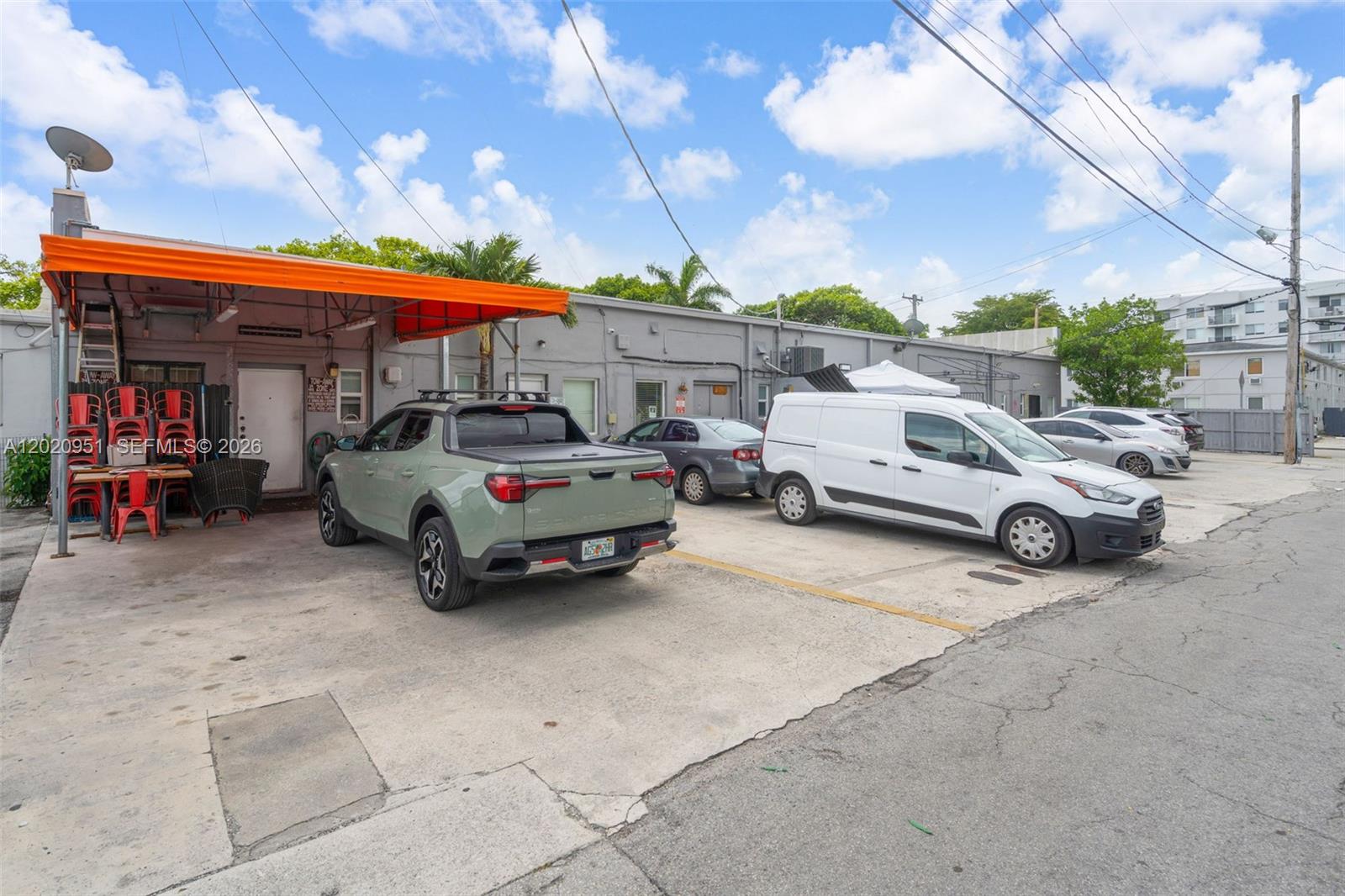 A parking lot sits in front of a gray commercial building with an orange awning — 2389 SW 22nd St, Miami FL 33145, MIAMI, FL