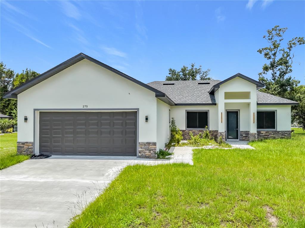 A single-story house with a two-car garage, stone accents, and a concrete driveway — 275 LECTURN STREET, PORT CHARLOTTE, FL