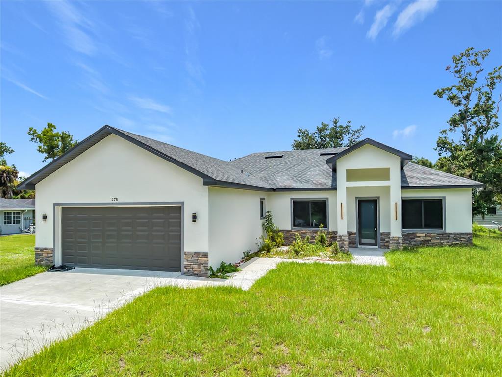 A single-story house with a two-car garage, stone accents, and a concrete walkway — 275 LECTURN STREET, PORT CHARLOTTE, FL