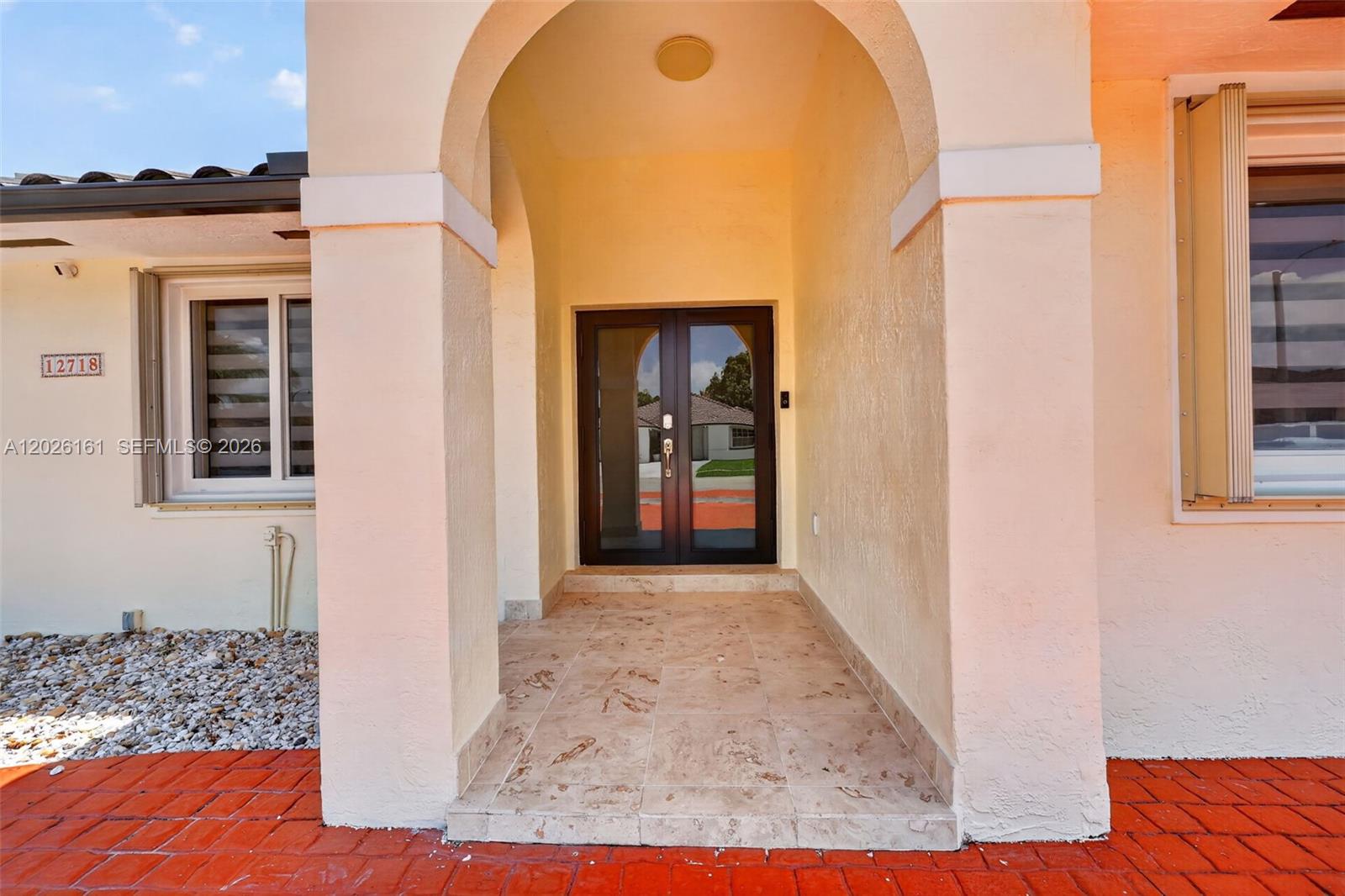The exterior entrance features a covered porch with tiled flooring and double glass doors — 12718 NW 6th Ln, Miami FL 33182, MIAMI, FL