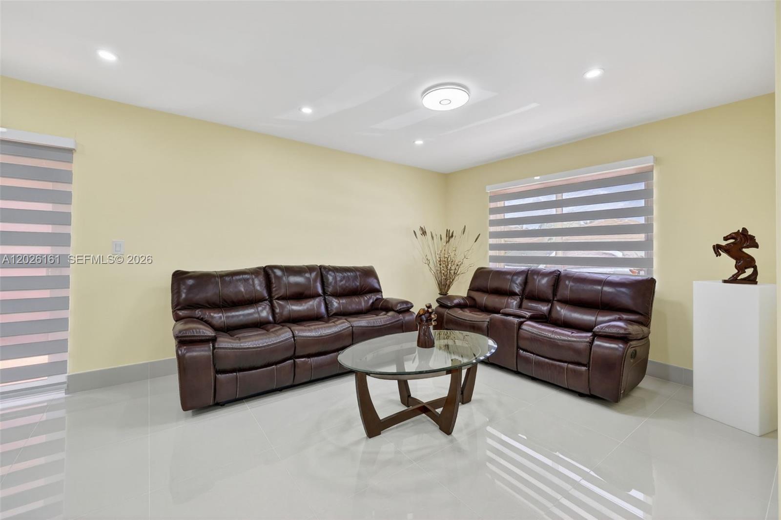 A living room features two brown leather sofas, a glass coffee table, and light walls — 12718 NW 6th Ln, Miami FL 33182, MIAMI, FL