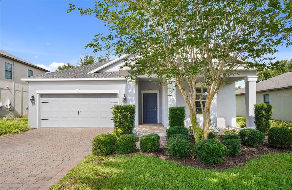A single-story house with a gray garage, blue front door, and manicured landscaping — 1950 PANTHEON DRIVE, WINTER GARDEN, FL