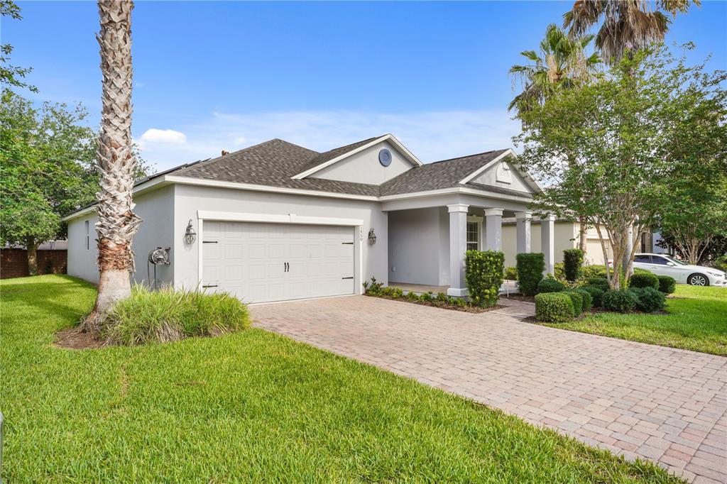 A single-story house with a gray stucco exterior, a two-car garage, and a paved driveway — 1950 PANTHEON DRIVE, WINTER GARDEN, FL