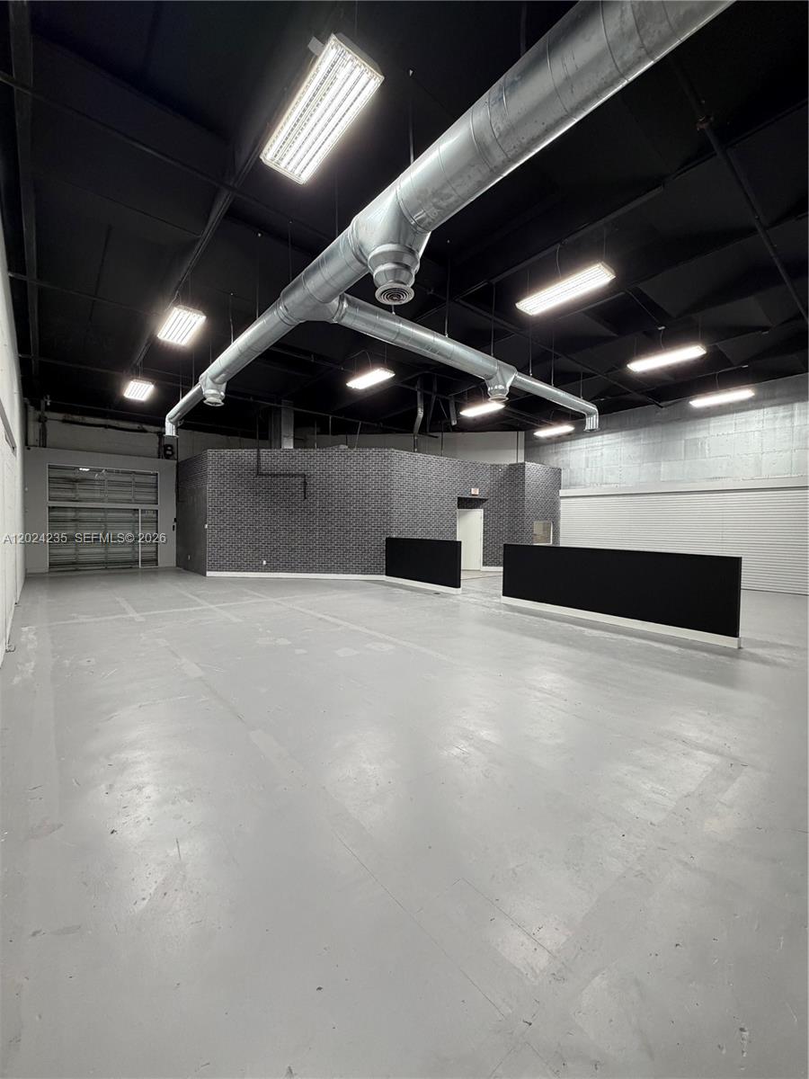 This industrial space features a gray concrete floor, exposed ceiling, and brick accent walls — 9450 NW 58th St # 3, Doral FL 33178, DORAL, FL