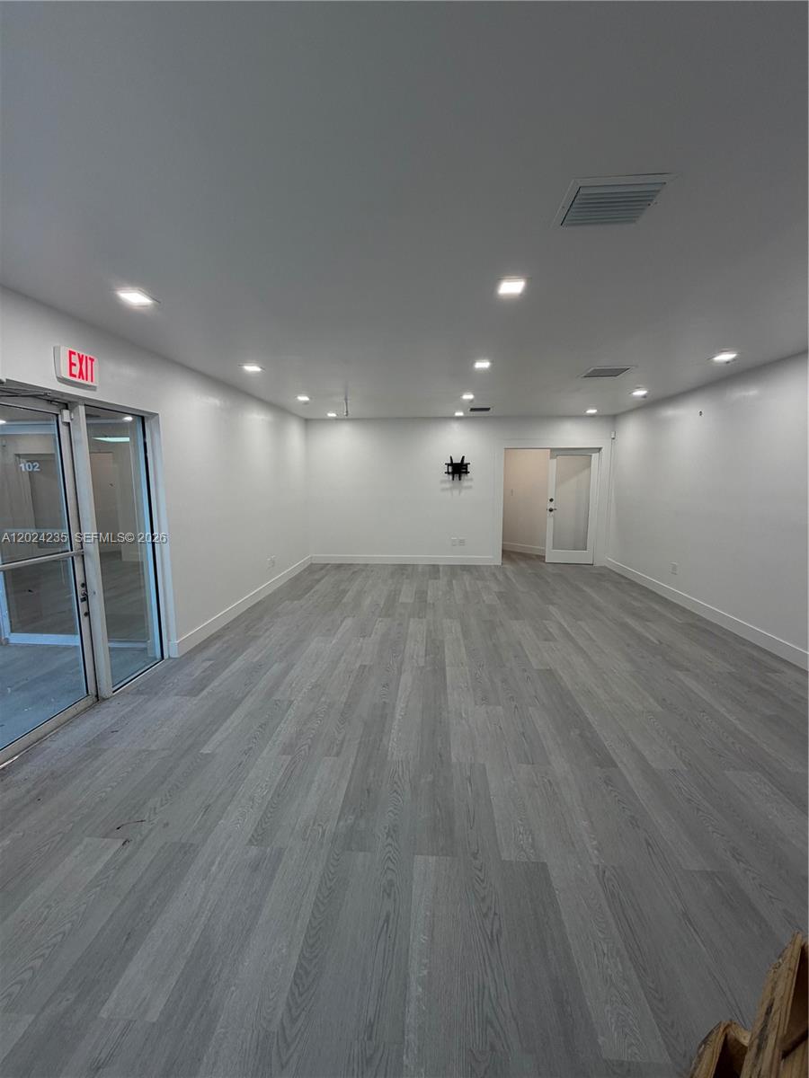 An empty commercial space features white walls, recessed lighting, and light gray wood-look flooring — 9450 NW 58th St # 3, Doral FL 33178, DORAL, FL
