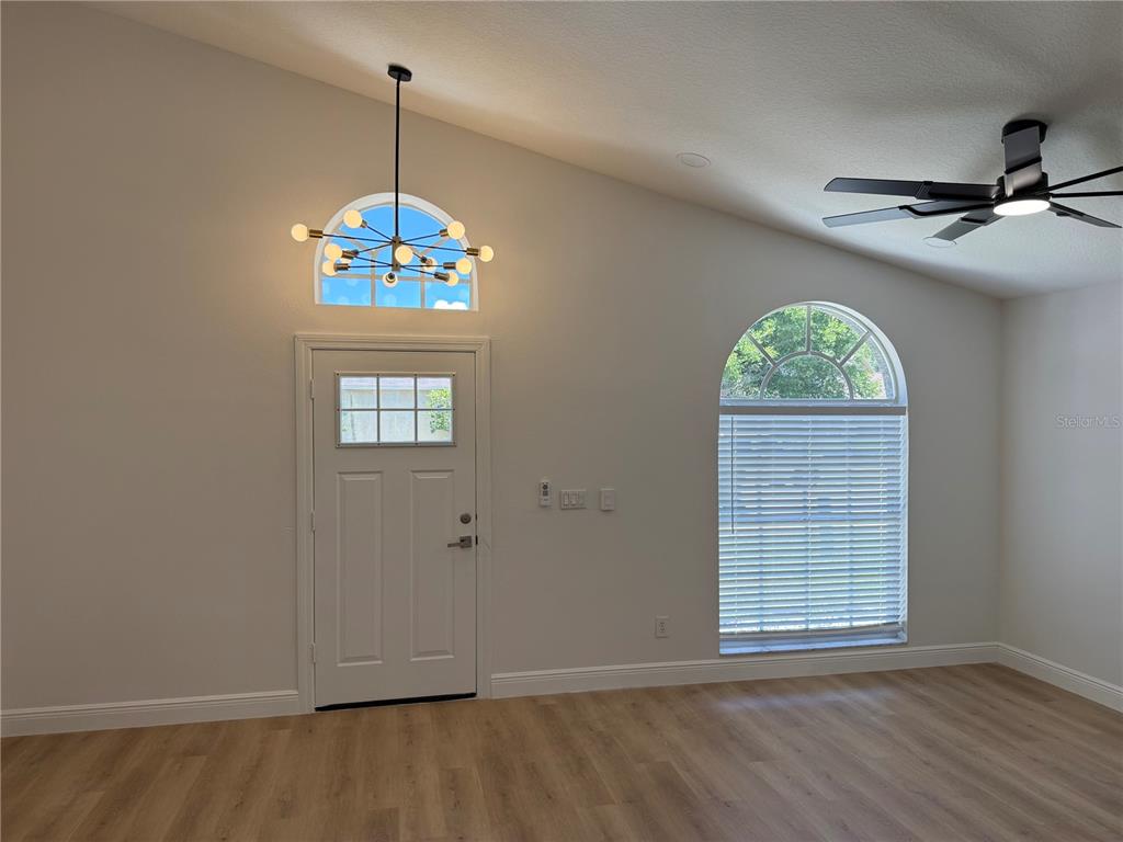 A room with light wood flooring, a vaulted ceiling, a chandelier, and two arched windows — 245 CHARDONNAY PLACE, VALRICO, FL