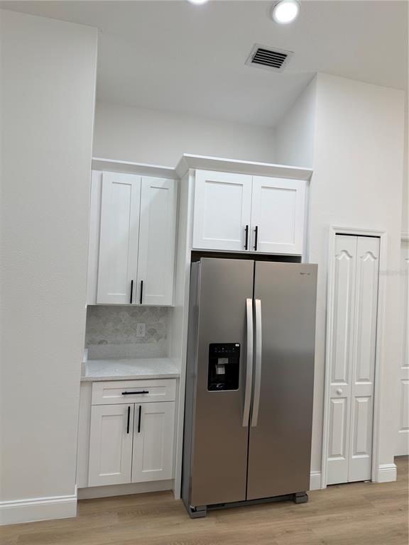 A kitchen features white cabinets, a stainless steel refrigerator, and a small countertop area — 245 CHARDONNAY PLACE, VALRICO, FL