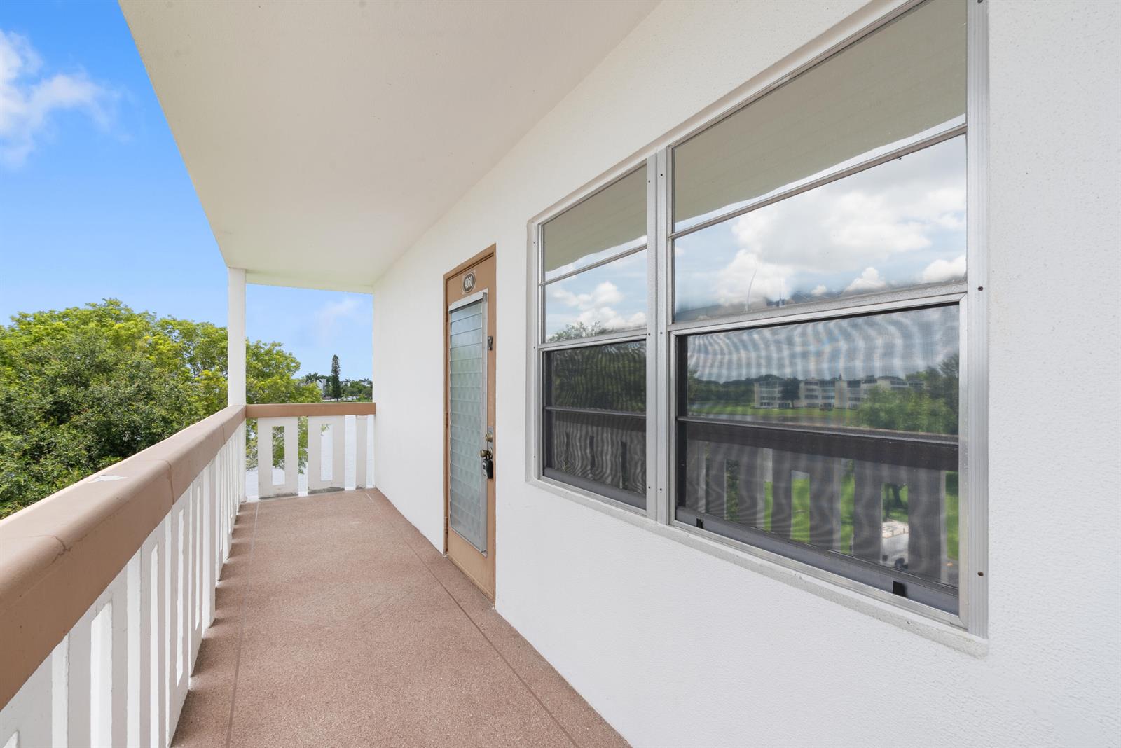 A balcony with a beige floor, white railing, and a door leading into a unit — 4060 Cornwall C, Boca Raton FL 33434, BOCA RATON, FL