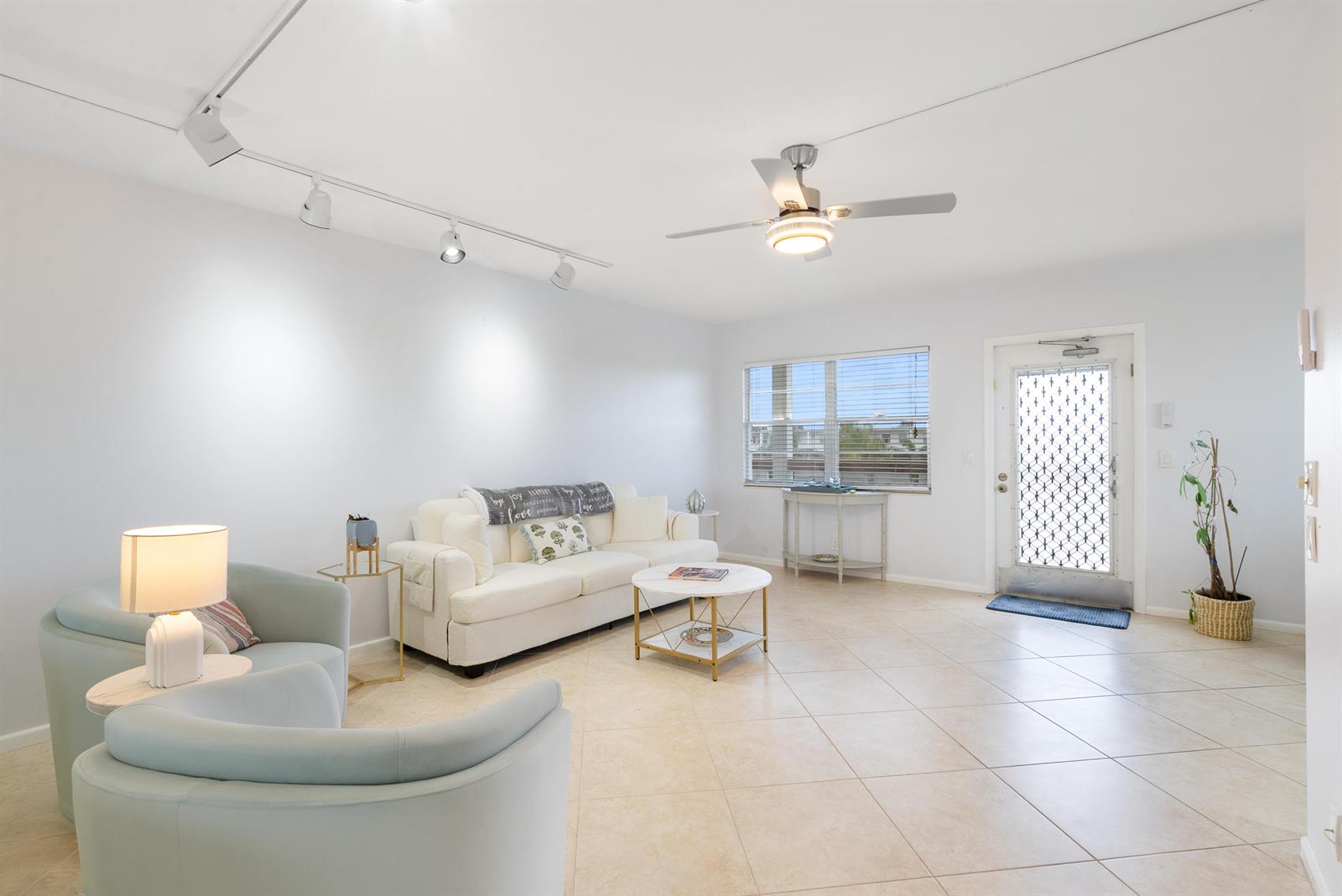 A bright living room features light tile flooring, a white sofa, and a ceiling fan — 4060 Cornwall C, Boca Raton FL 33434, BOCA RATON, FL