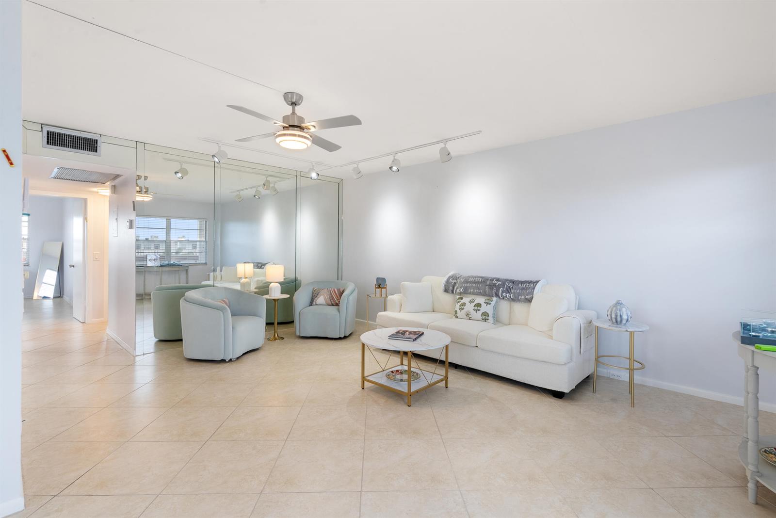 A living room features a white sofa, two light blue armchairs, and a mirrored wall — 4060 Cornwall C, Boca Raton FL 33434, BOCA RATON, FL
