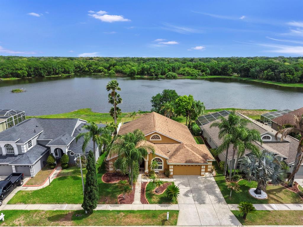 An aerial view of a suburban house with a tan roof situated beside a lake — 220 ROSANA DRIVE, BRANDON, FL