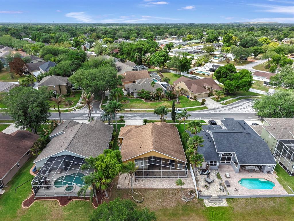 An aerial view shows three suburban houses with swimming pools and screened lanais — 220 ROSANA DRIVE, BRANDON, FL