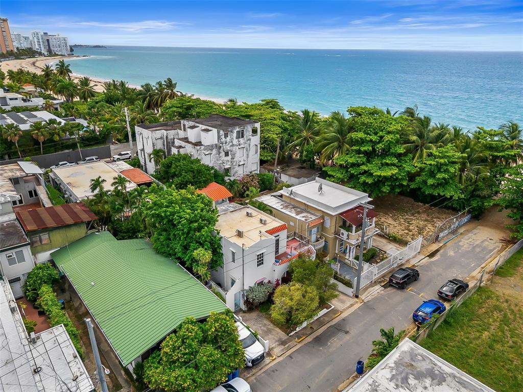 An aerial view shows several houses near a beach with palm trees and parked cars — 6 GERTRUDIS, SAN JUAN, PR