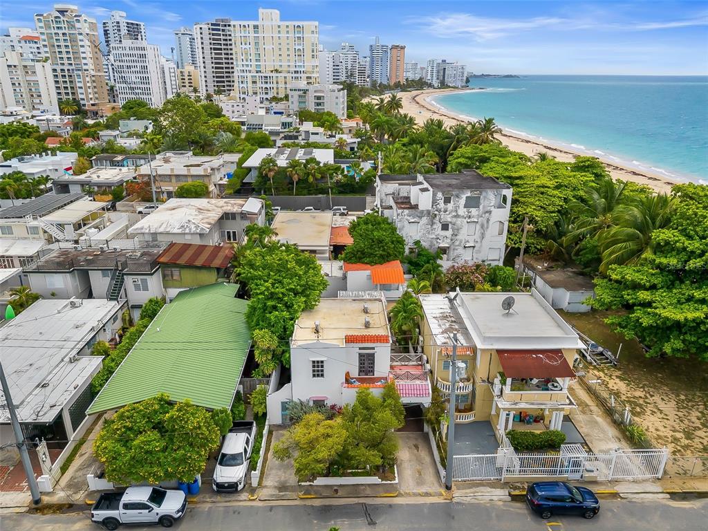 An aerial view shows residential buildings near a sandy beach and a city skyline — 6 GERTRUDIS, SAN JUAN, PR