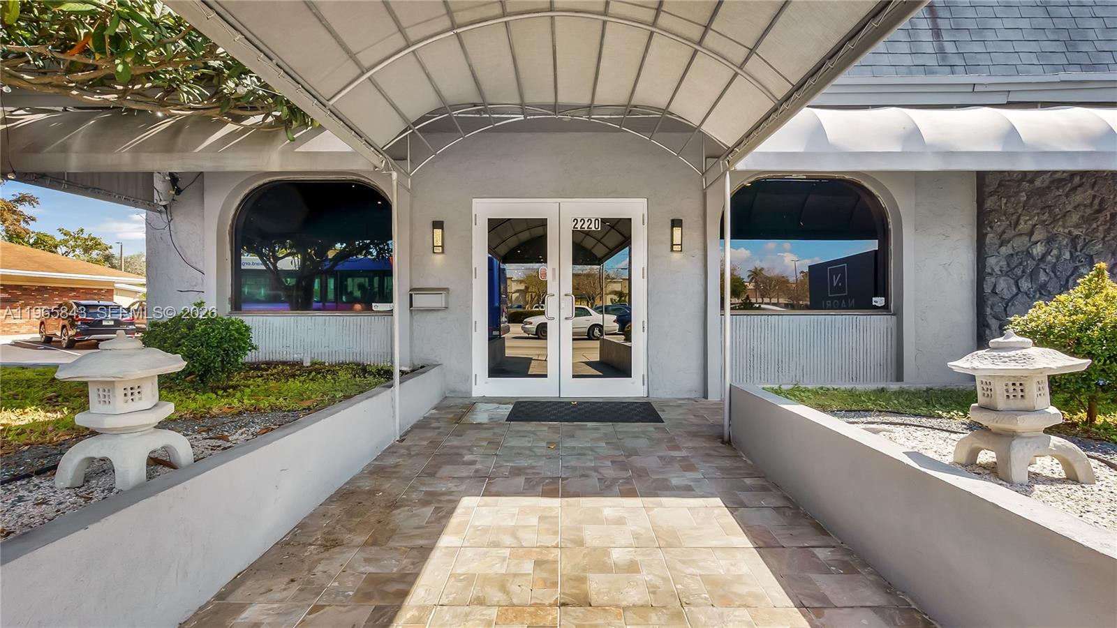 The exterior entrance features a covered walkway, double glass doors, and two stone lanterns — 2220 N University Dr, Sunrise FL 33322, SUNRISE, FL