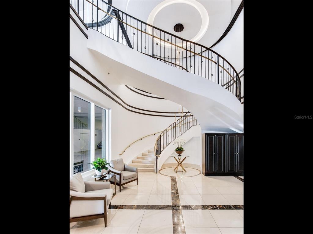 A grand foyer features a curved staircase, white tile flooring, and two armchairs — 3507 BAYSHORE BOULEVARD UNIT 303, TAMPA, FL