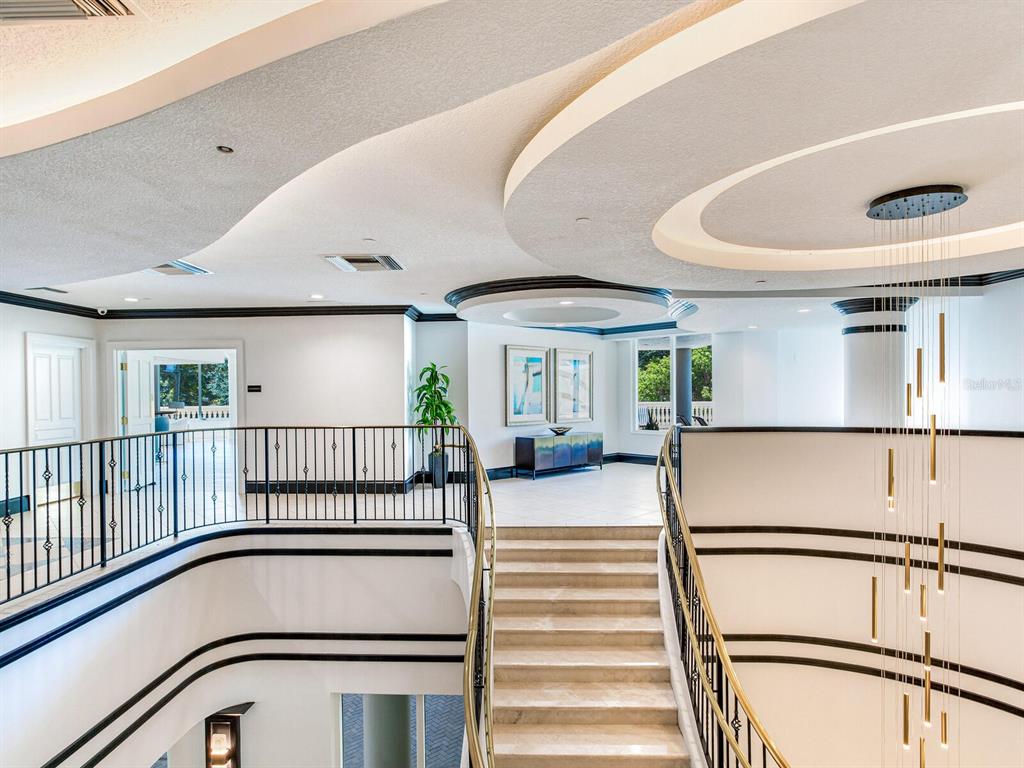 A grand staircase with a metal railing leads to a landing with recessed ceiling lighting — 3507 BAYSHORE BOULEVARD UNIT 303, TAMPA, FL