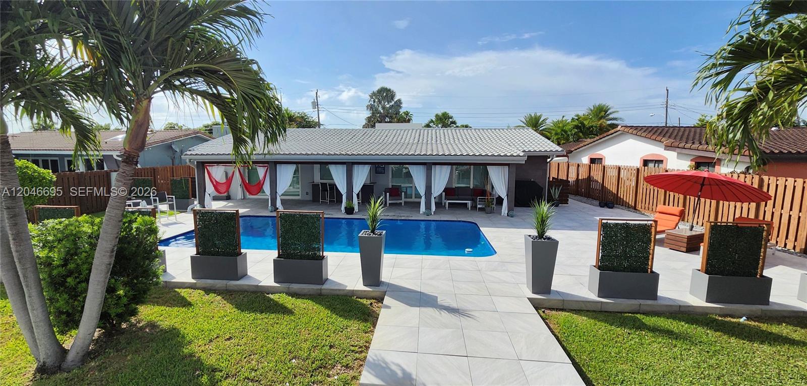 A backyard features a swimming pool, a covered patio with white curtains, and tile flooring — 966 SE 9th Ave, Pompano Beach FL 33060, POMPANO BEACH, FL