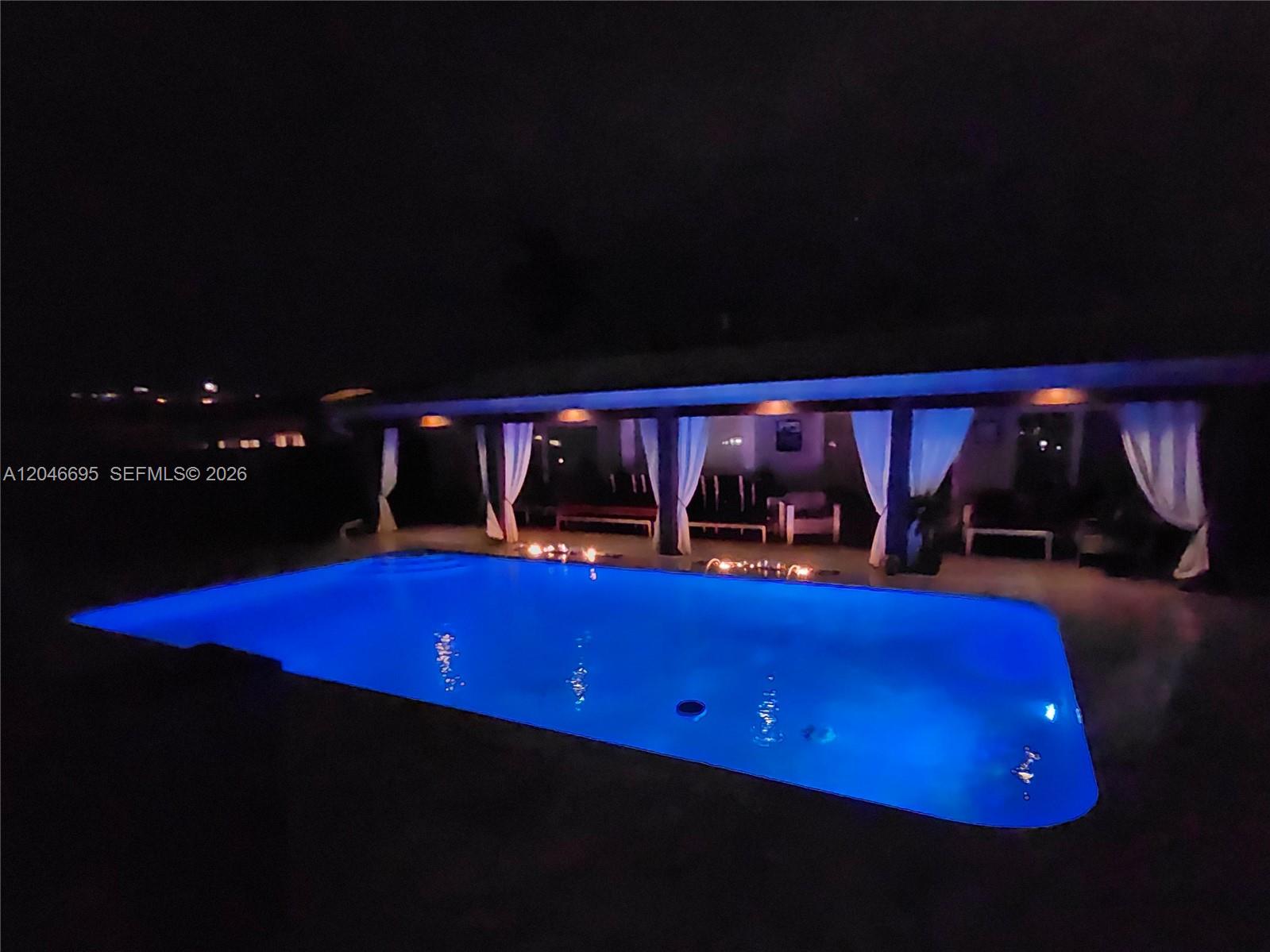 A rectangular swimming pool with blue lighting sits in front of a covered patio area — 966 SE 9th Ave, Pompano Beach FL 33060, POMPANO BEACH, FL