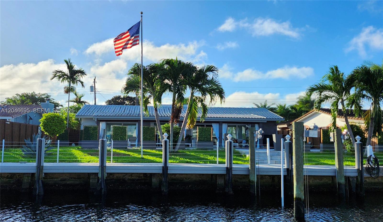 A waterfront house features a dock, a grassy lawn, and an American flag on a pole — 966 SE 9th Ave, Pompano Beach FL 33060, POMPANO BEACH, FL