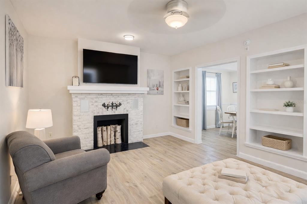 A living room features a white brick fireplace, built-in shelving, a gray armchair, and light flooring — 501 S MAGNOLIA AVENUE UNIT 1, TAMPA, FL