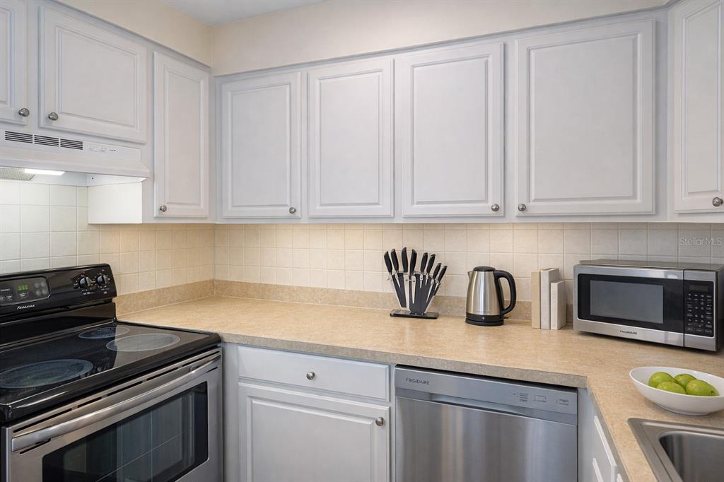 A kitchen with white cabinets, beige countertops, stainless steel appliances, and a tiled backsplash — 501 S MAGNOLIA AVENUE UNIT 1, TAMPA, FL