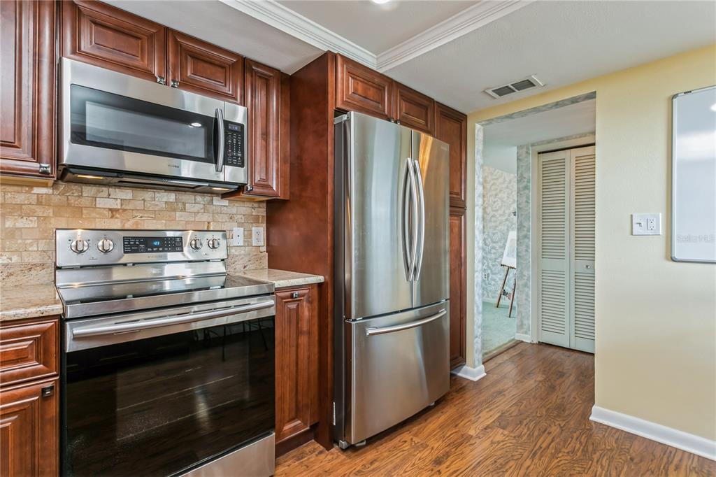 A kitchen with stainless steel appliances, dark wood cabinets, and a stone tile backsplash — 5200 BRITTANY DRIVE S UNIT 1708, ST PETERSBURG, FL