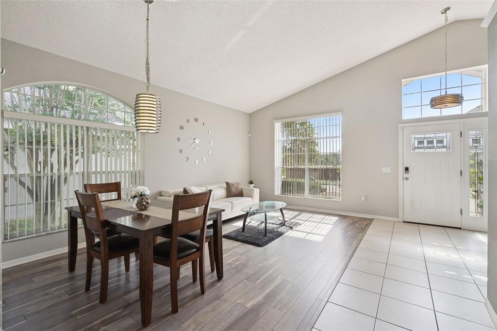 A dining and living area with wood floors, a large wall clock, and vaulted ceilings — 2712 BIRMINGHAM BOULEVARD, ORLANDO, FL