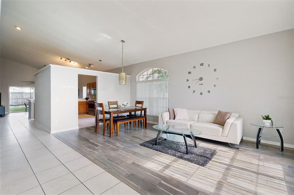 A living and dining area features wood-look flooring, a white sofa, and a wall clock — 2712 BIRMINGHAM BOULEVARD, ORLANDO, FL