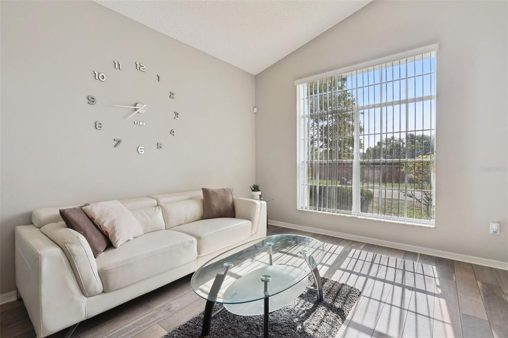 A living room features a white sofa, glass coffee table, and a large wall clock — 2712 BIRMINGHAM BOULEVARD, ORLANDO, FL