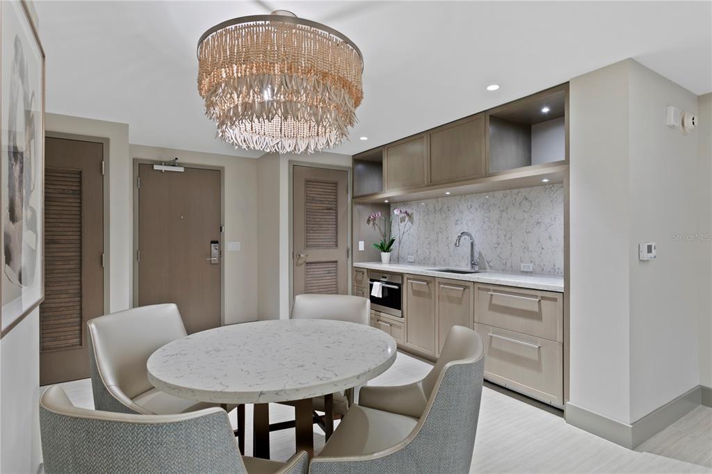 A dining area features a round marble table, four upholstered chairs, and a small kitchenette — 691 S GULFVIEW BOULEVARD UNIT 1408, CLEARWATER BEACH, FL