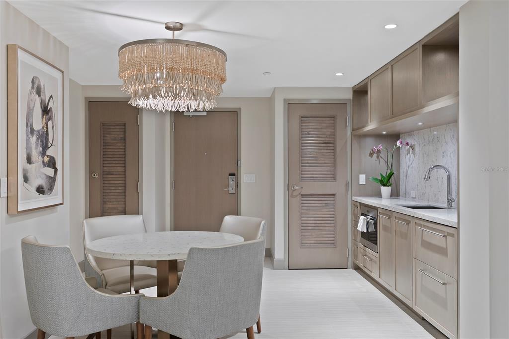 A dining area with a round table, four chairs, a chandelier, and a kitchenette — 691 S GULFVIEW BOULEVARD UNIT 1408, CLEARWATER BEACH, FL