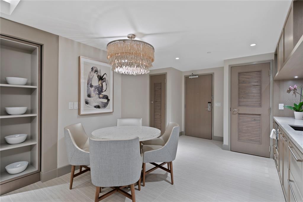 A dining area features a round marble table, four upholstered chairs, and a beaded chandelier — 691 S GULFVIEW BOULEVARD UNIT 1408, CLEARWATER BEACH, FL