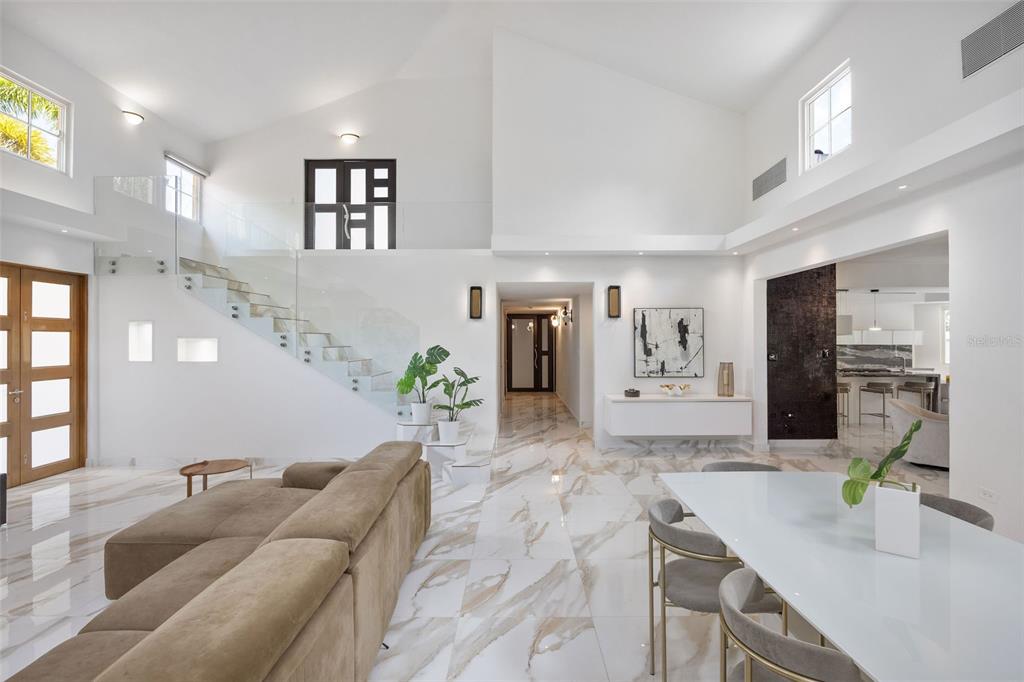 A bright, open-concept living and dining area features white marble floors and a glass staircase — 415 CAMINO DEL SUSUA, DORADO, PR