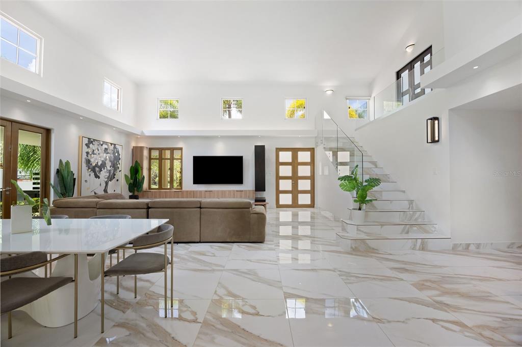 A bright, open-concept living room features white marble floors, a large sectional, and a staircase — 415 CAMINO DEL SUSUA, DORADO, PR