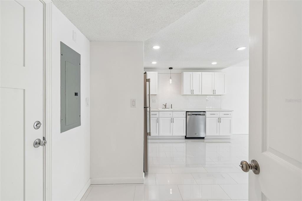 A view through a doorway into a bright kitchen with white cabinets and tile floors — 450 TREASURE ISLAND CAUSEWAY UNIT 106, TREASURE ISLAND, FL