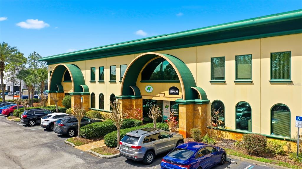 An exterior view of a two-story commercial building with green arched accents and parking — 6881 KINGSPOINTE PARKWAY UNIT 3, ORLANDO, FL