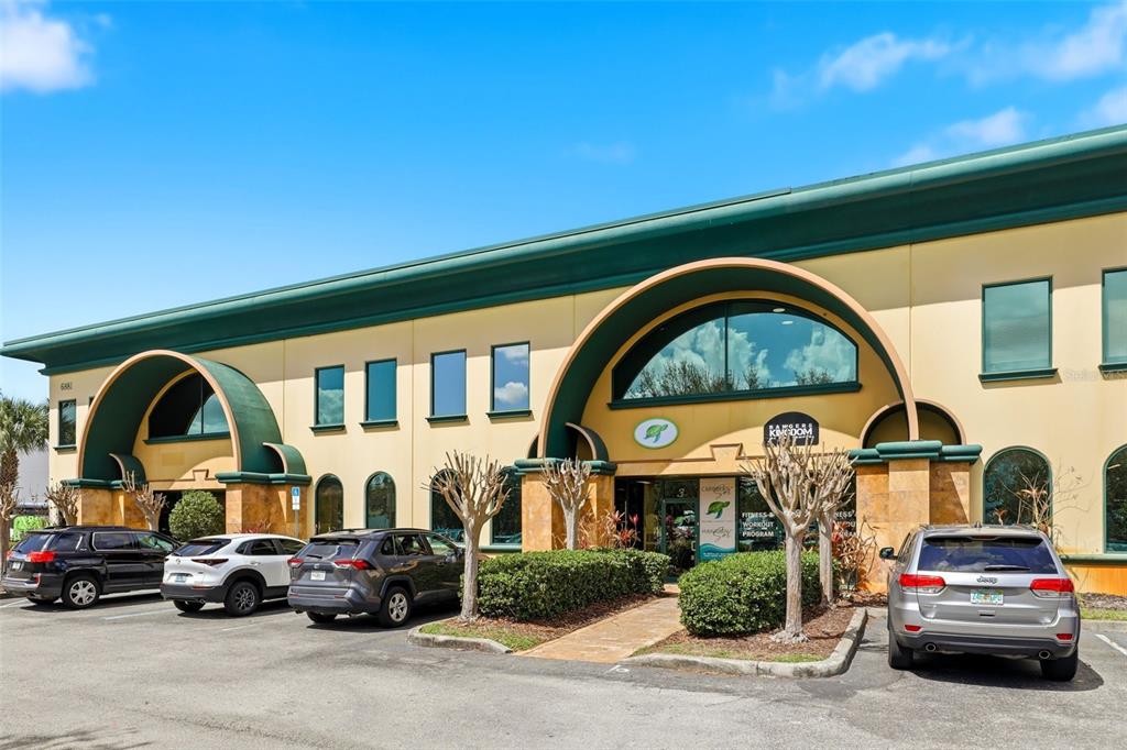 A two-story commercial building with a tan facade, green trim, and a parking lot — 6881 KINGSPOINTE PARKWAY UNIT 3, ORLANDO, FL