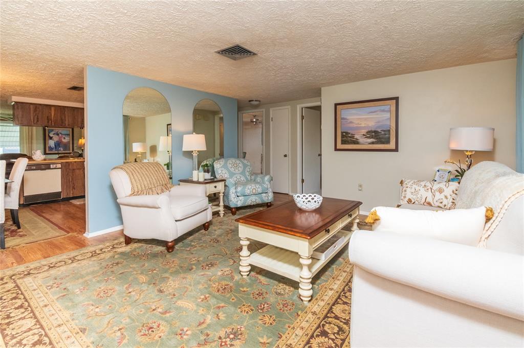 A living room features a patterned rug, arched mirrors, a coffee table, and upholstered seating — 6710 RANCHWOOD LOOP, NEW PORT RICHEY, FL