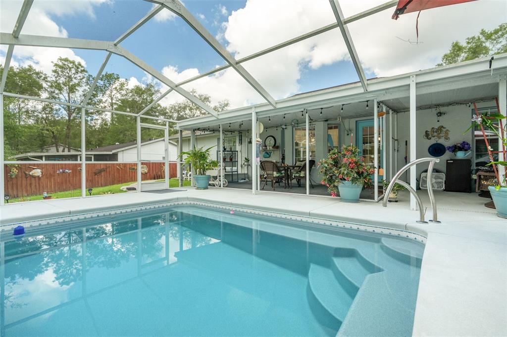 A swimming pool with steps sits inside a screened-in patio area next to a house — 4025 S LINWOOD TERRACE, INVERNESS, FL
