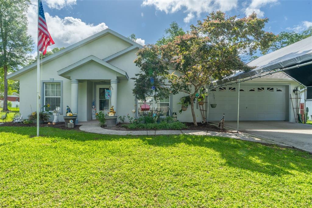 A single-story house with a light-colored exterior, a front porch, and a carport over the driveway — 4025 S LINWOOD TERRACE, INVERNESS, FL