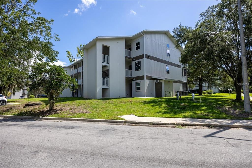 A three-story apartment building with light-colored siding and an exterior staircase — 6519 W NEWBERRY ROAD UNIT 412, GAINESVILLE, FL